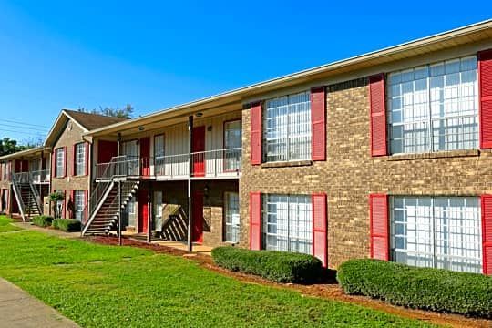 A large apartment building with a lot of windows and red shutters.