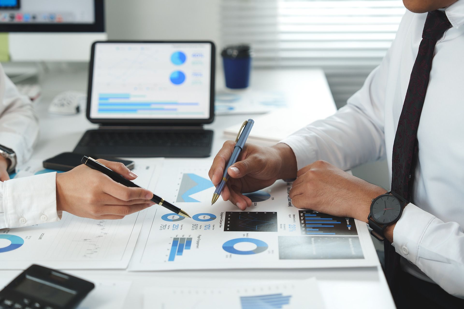 People reviewing charts and graphs on paper and a tablet.
