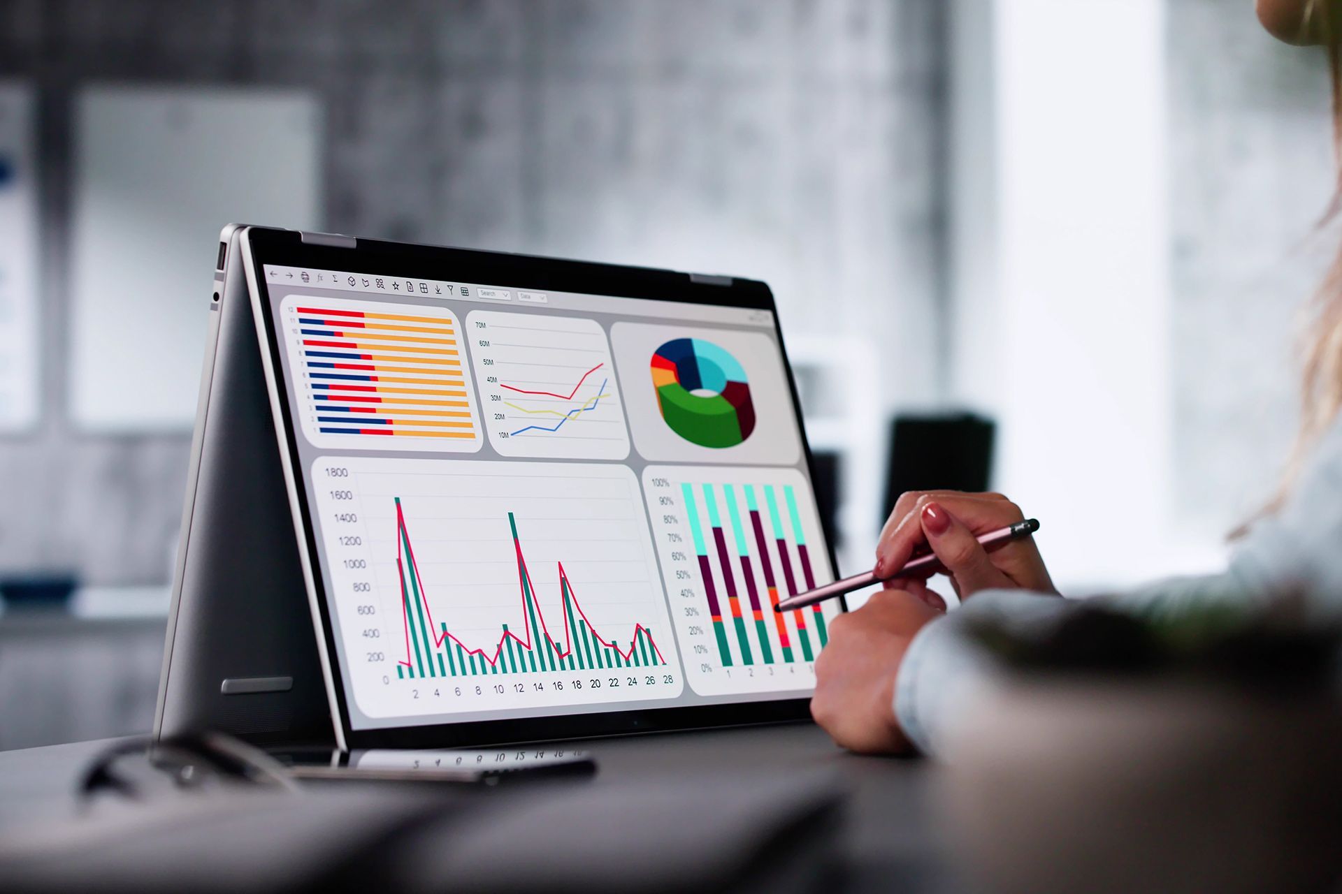 Person using a laptop displaying financial charts and graphs; indoors.