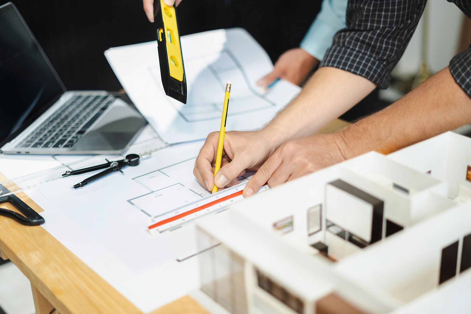 Architects reviewing blueprints with model and tools on desk.