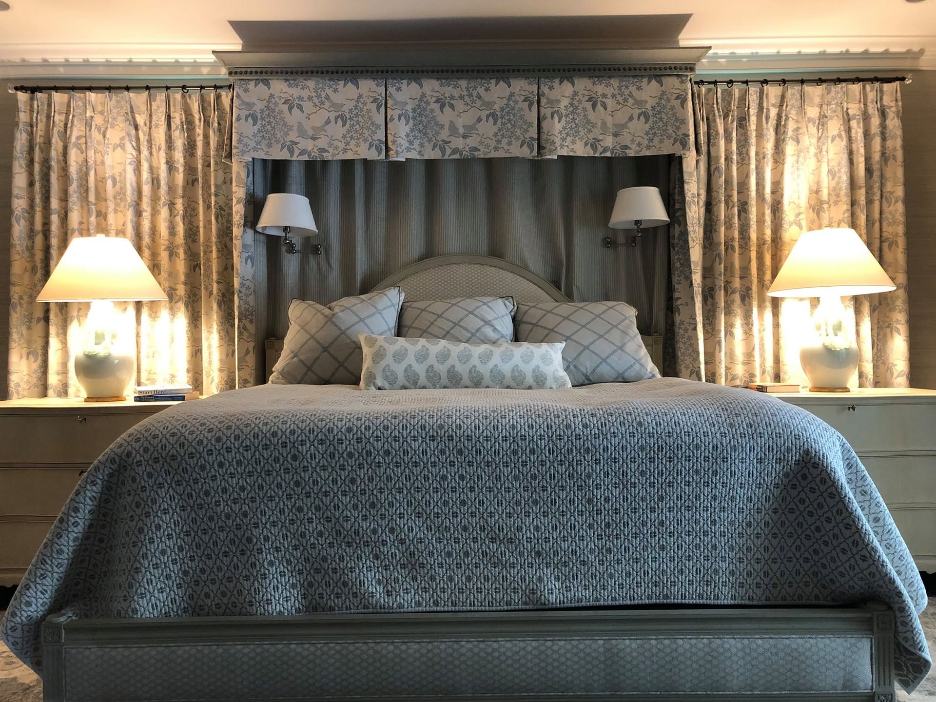 Elegant bedroom with a large tufted bed, bedside lamps, and patterned drapes