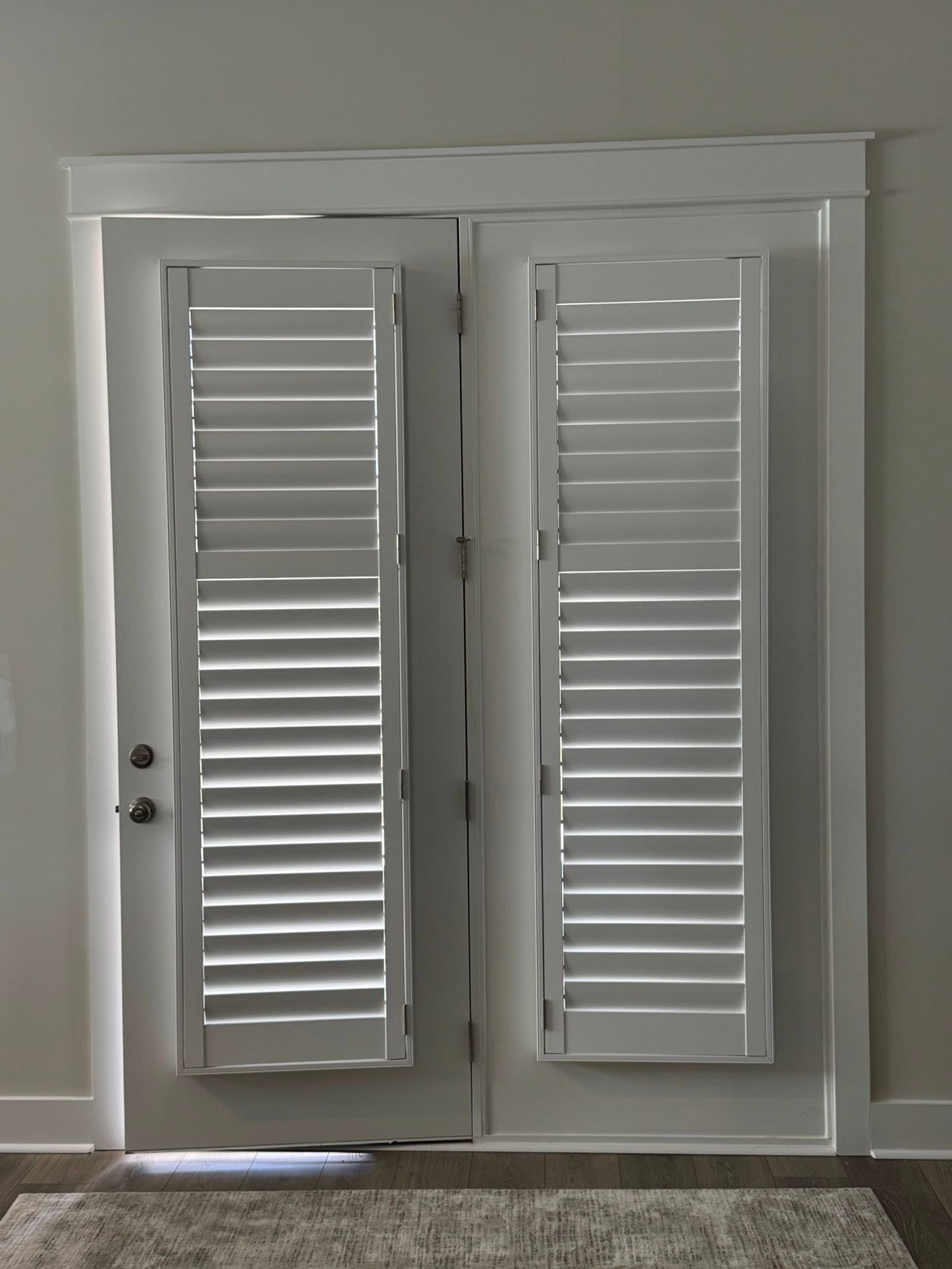 White French doors with closed plantation shutters in a gray-walled room.