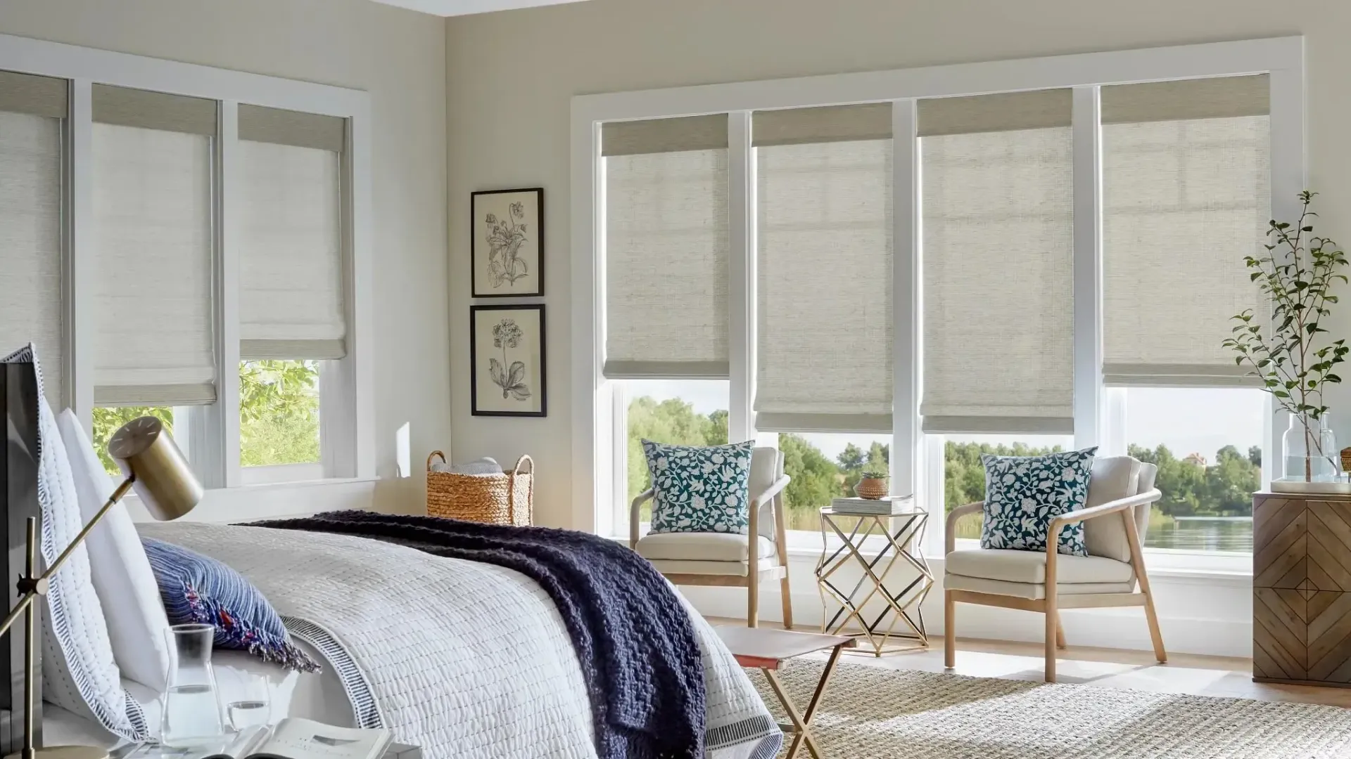 Bright sunroom bedroom with white walls, woven chairs, patterned rug, and large windows with blinds