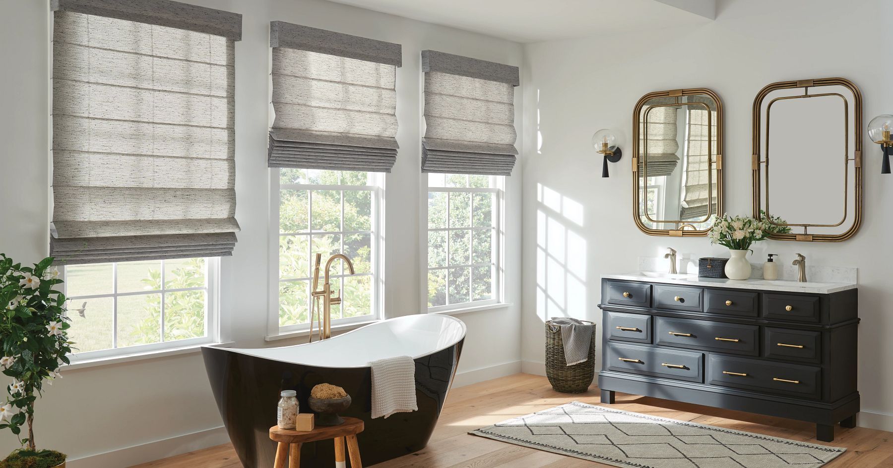 Bright living room with large windows, Roman shades, a dark dresser with mirrors, and a striped rug