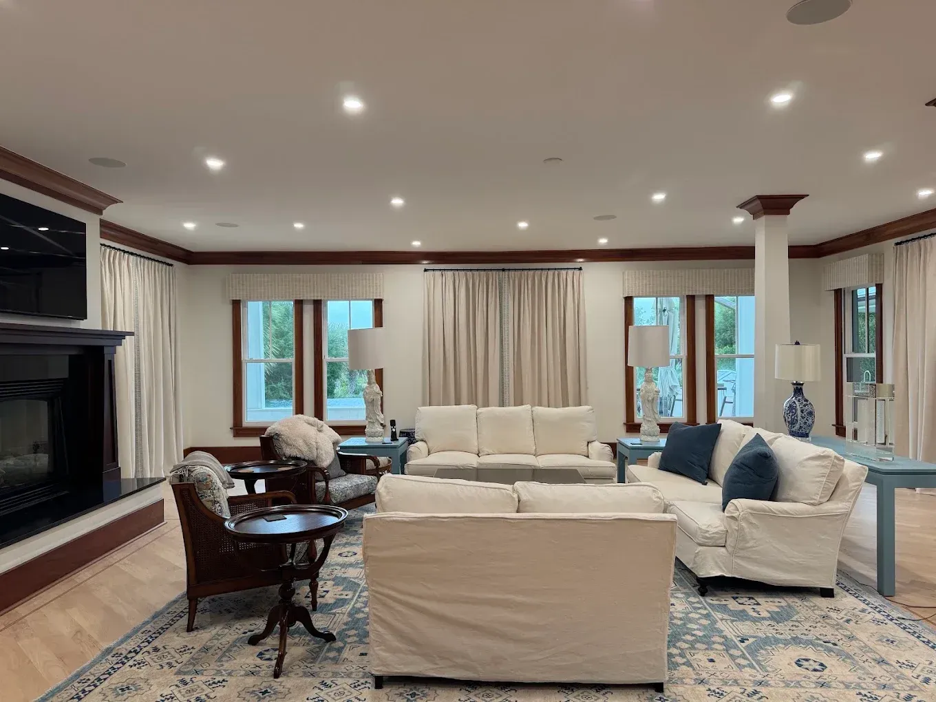 Spacious beige living room with sofas, fireplace, dining table, and large windows.