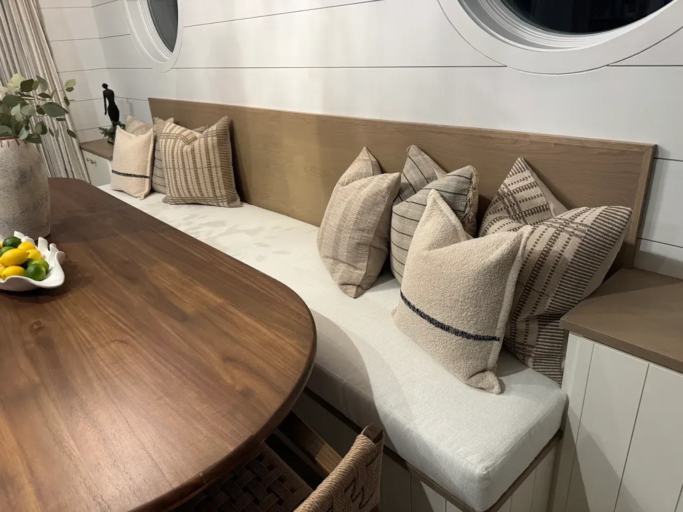 Cozy restaurant booth with beige cushions, wooden table, and round window accents