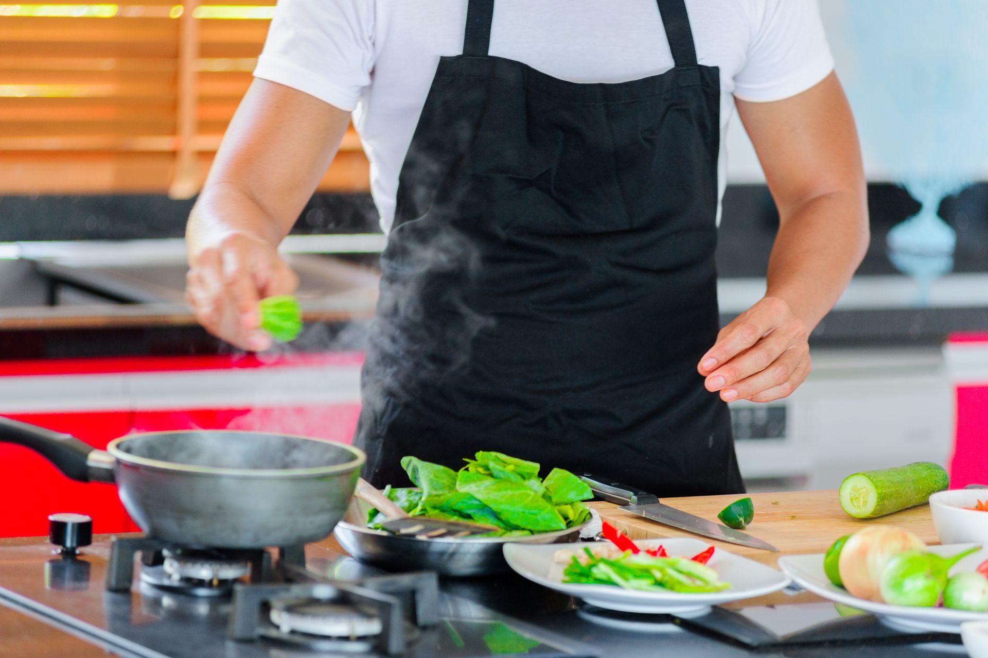 A man in an apron is cooking vegetables in a kitchen. A man in an apron is cooking vegetables in a kitchen.