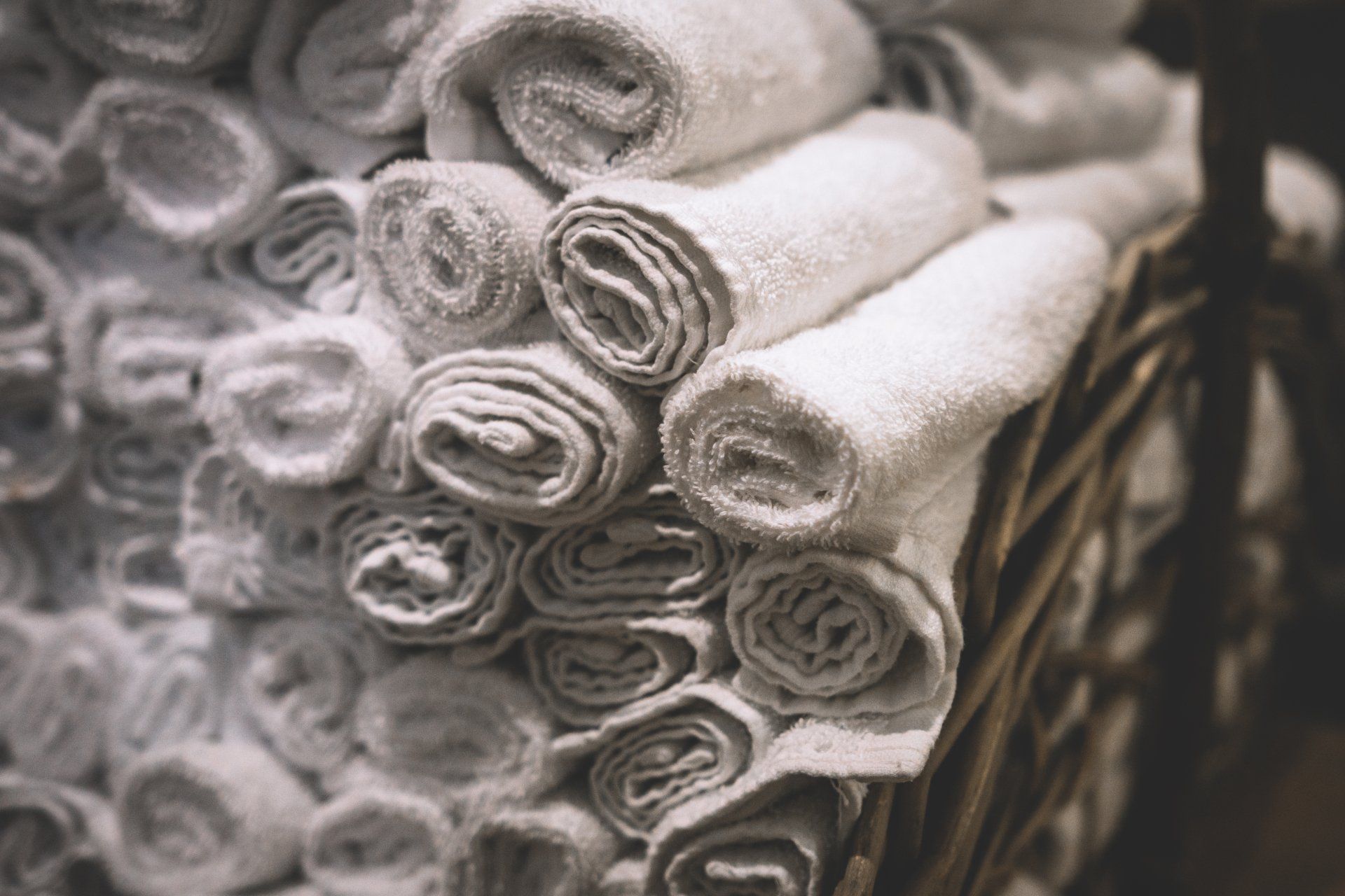 A bunch of towels are rolled up in a basket. A bunch of towels are rolled up in a basket.