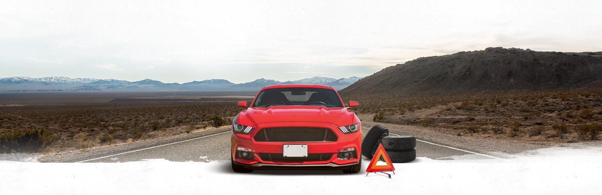 Red sports car on a snowy road with a warning cone and equipment in the foreground | Automotive Physicians