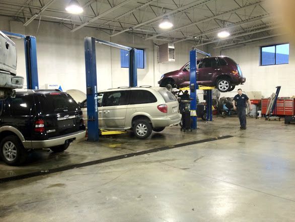 Auto repair shop with several vehicles on lifts and a mechanic working nearby | Automotive Physicians