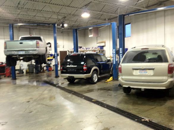 Auto repair shop with three vehicles on lifts and parked in service bays | Automotive Physicians