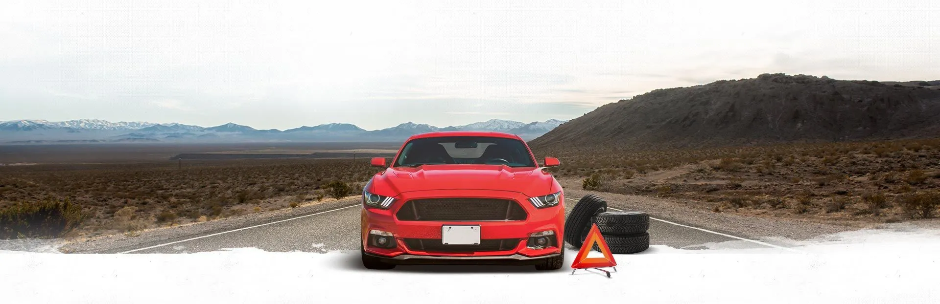 Red sports car on a snowy road with a warning cone and equipment in the foreground | Automotive Physicians