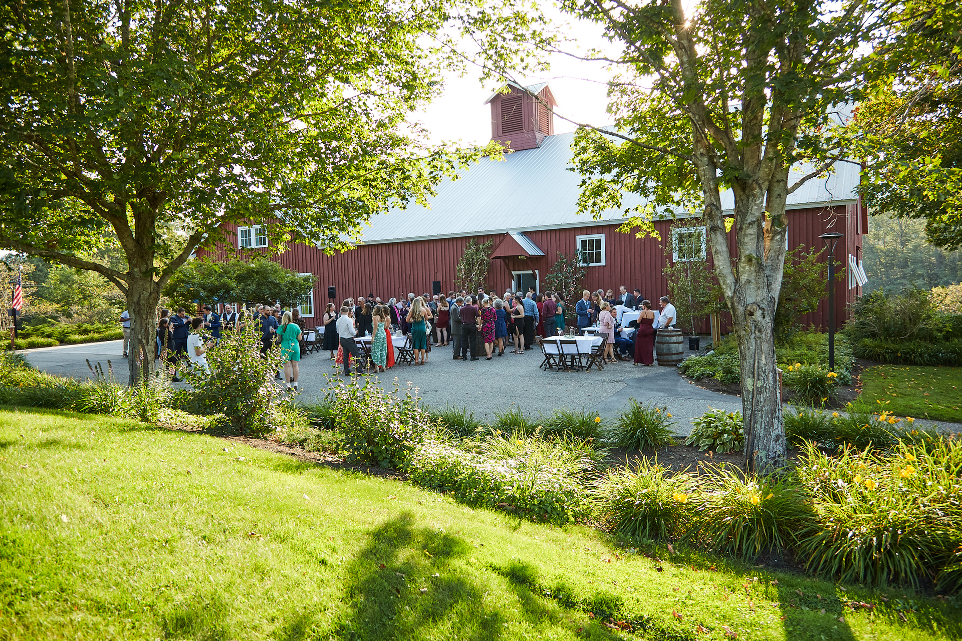 A large group of people are standing in front of a large red barn.