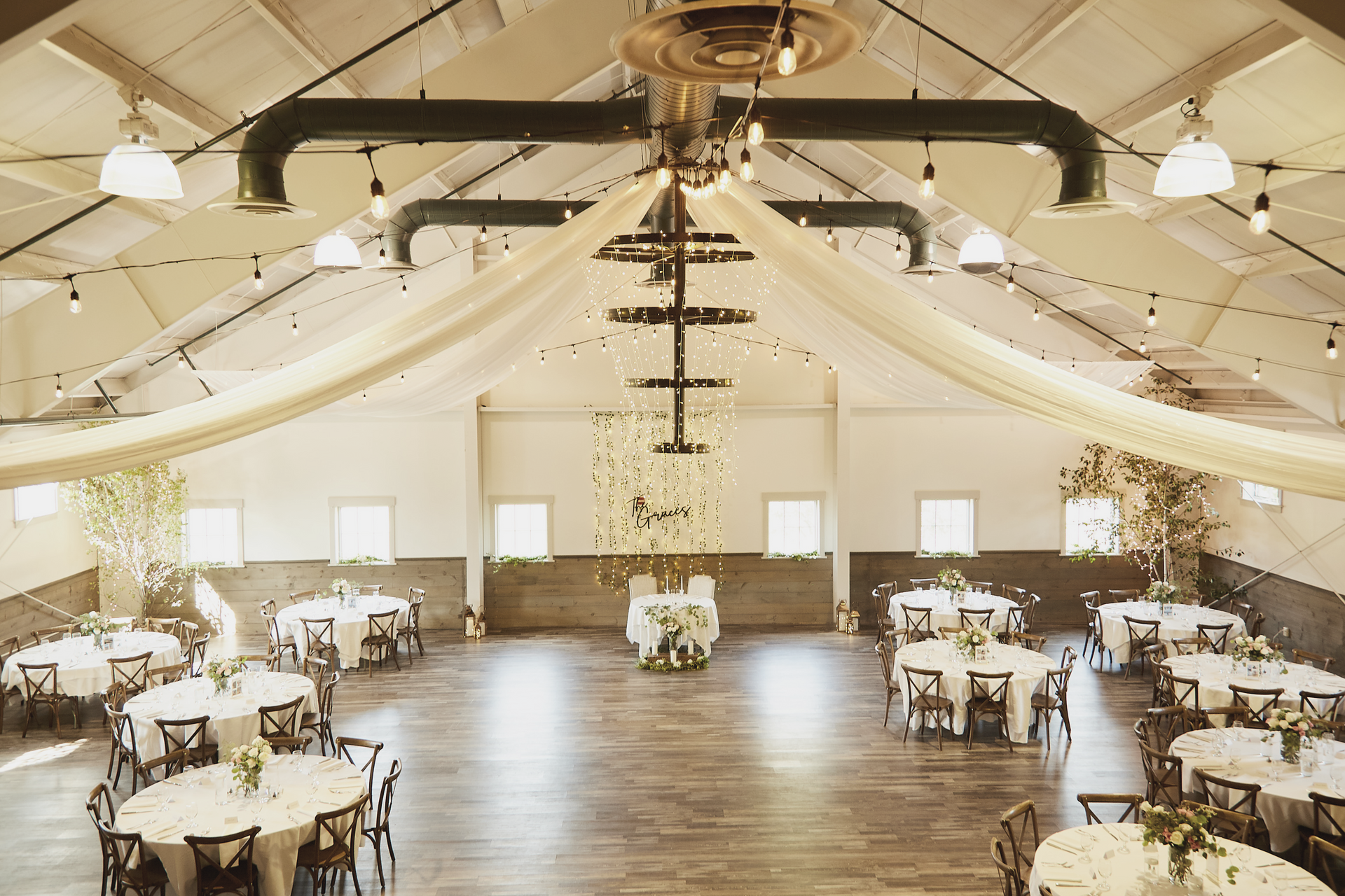 A large room with tables and chairs set up for a wedding reception.