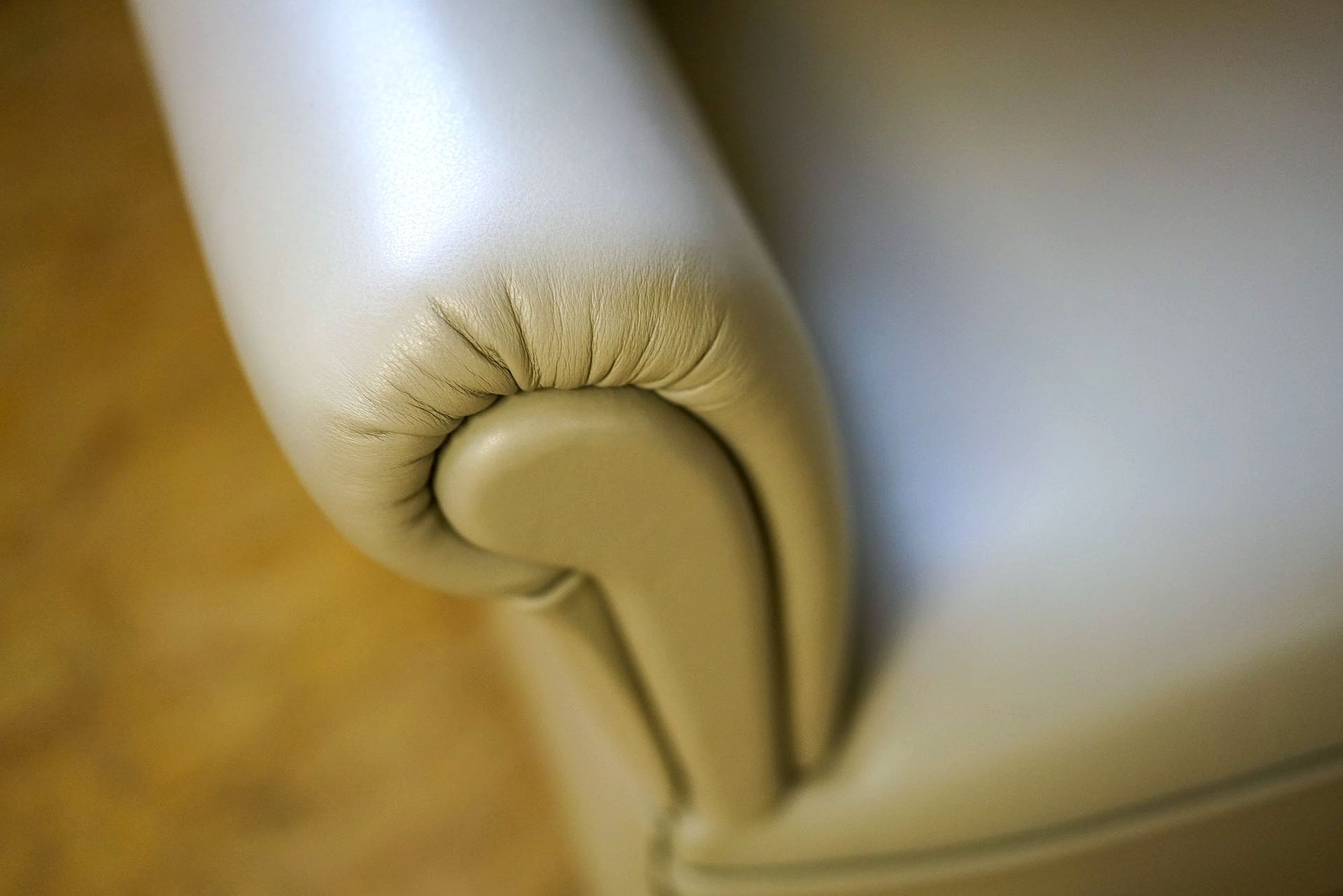 Een close-up van de armleuning van een witte leren fauteuil