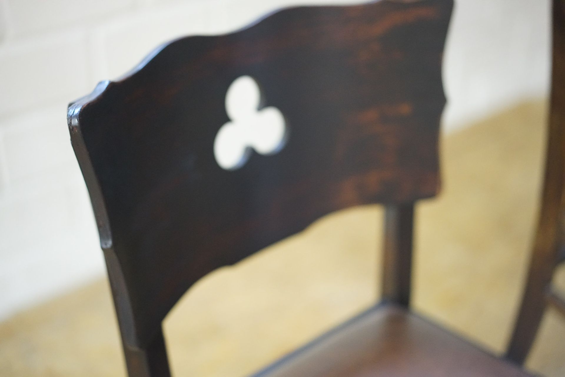 Een close-up van een houten stoel met een klavertje op de rug