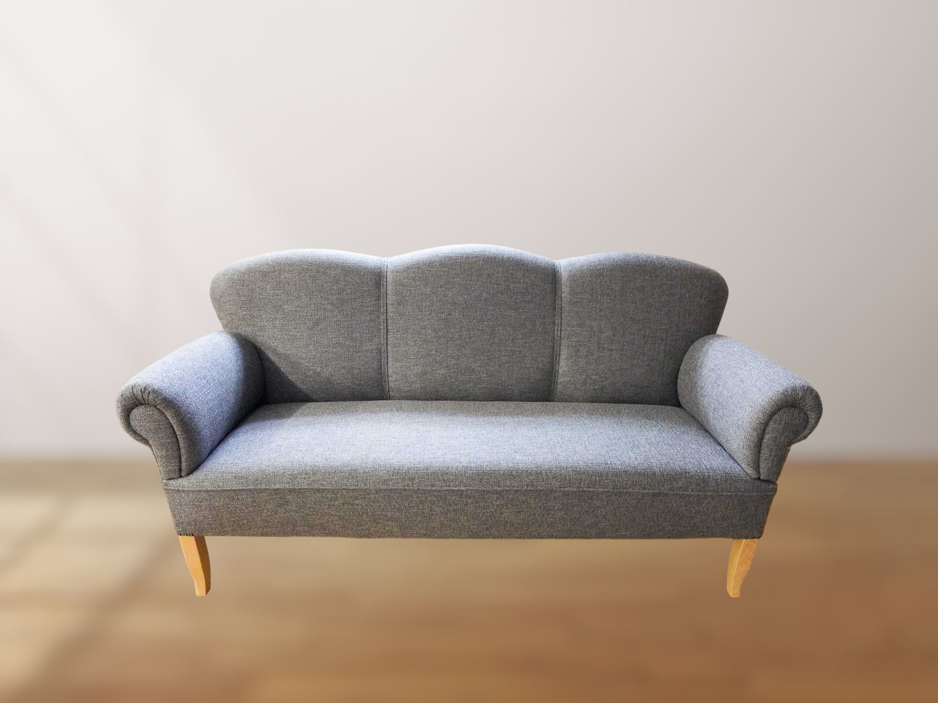 Ein graues Sofa steht auf einem Holzboden vor einer weißen Wand