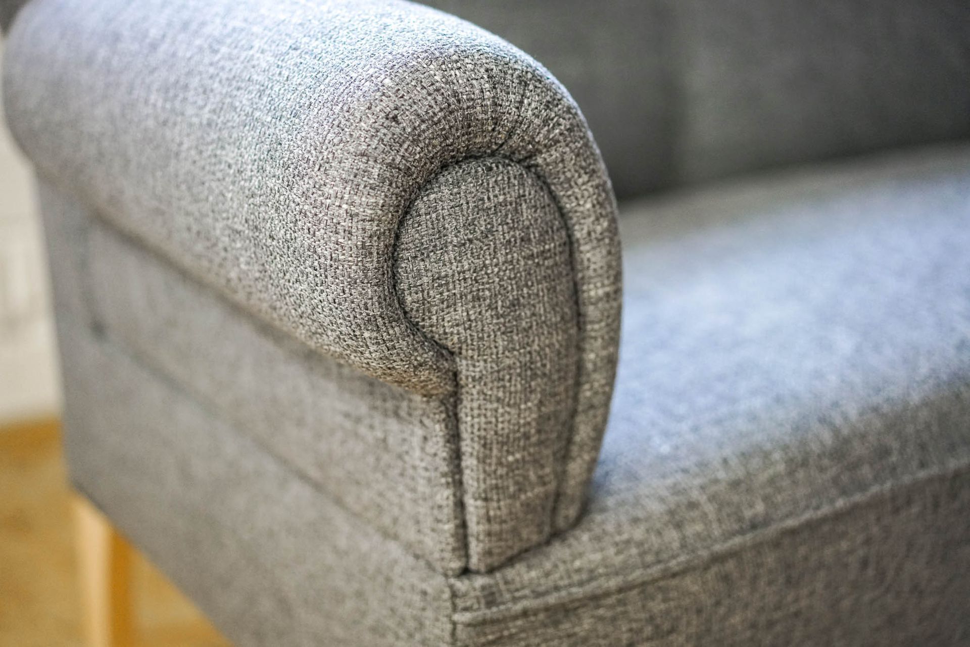 Eine Nahaufnahme der Armlehne eines grauen Sofas