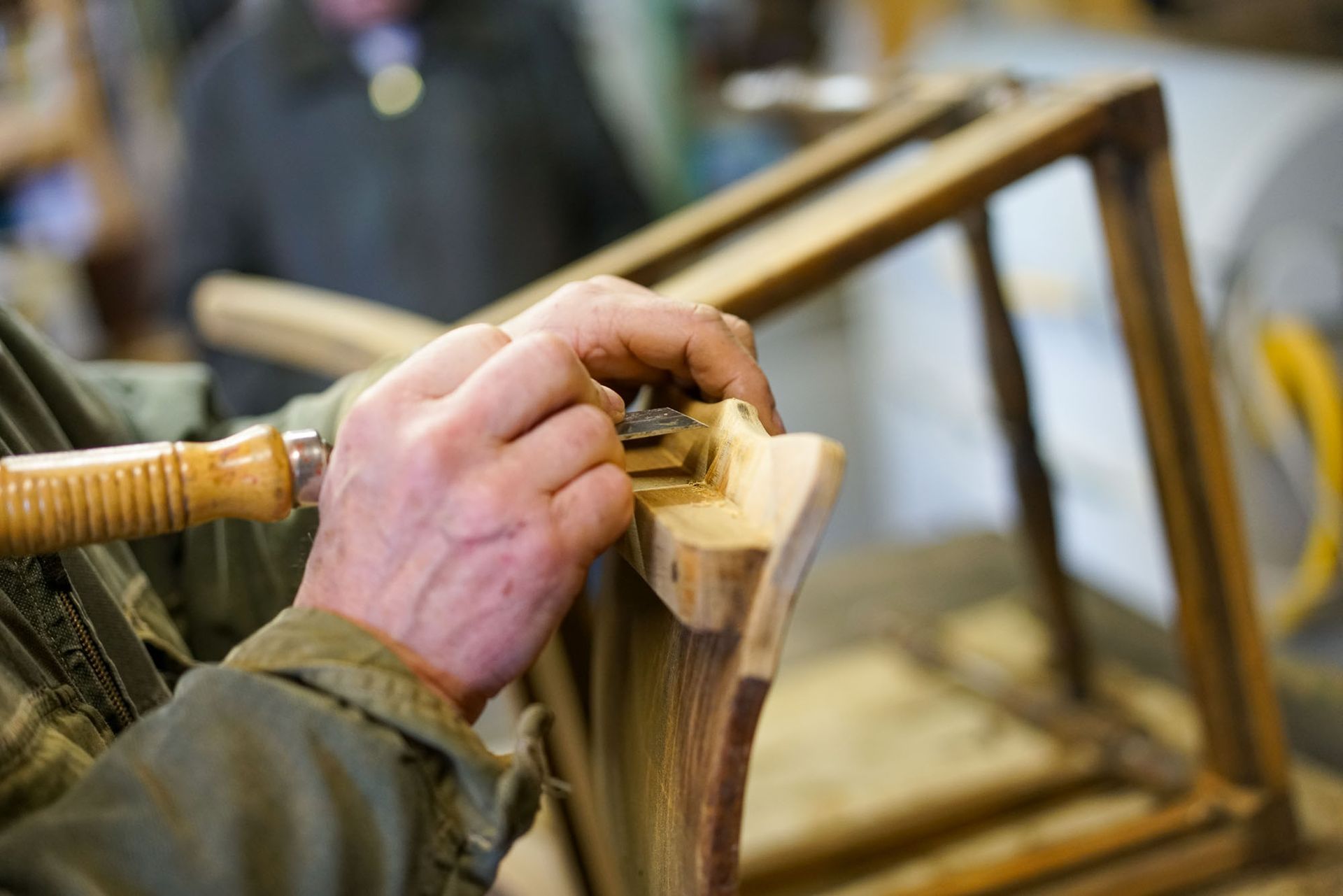 Ein Mann schnitzt mit einem Meißel ein Stück Holz