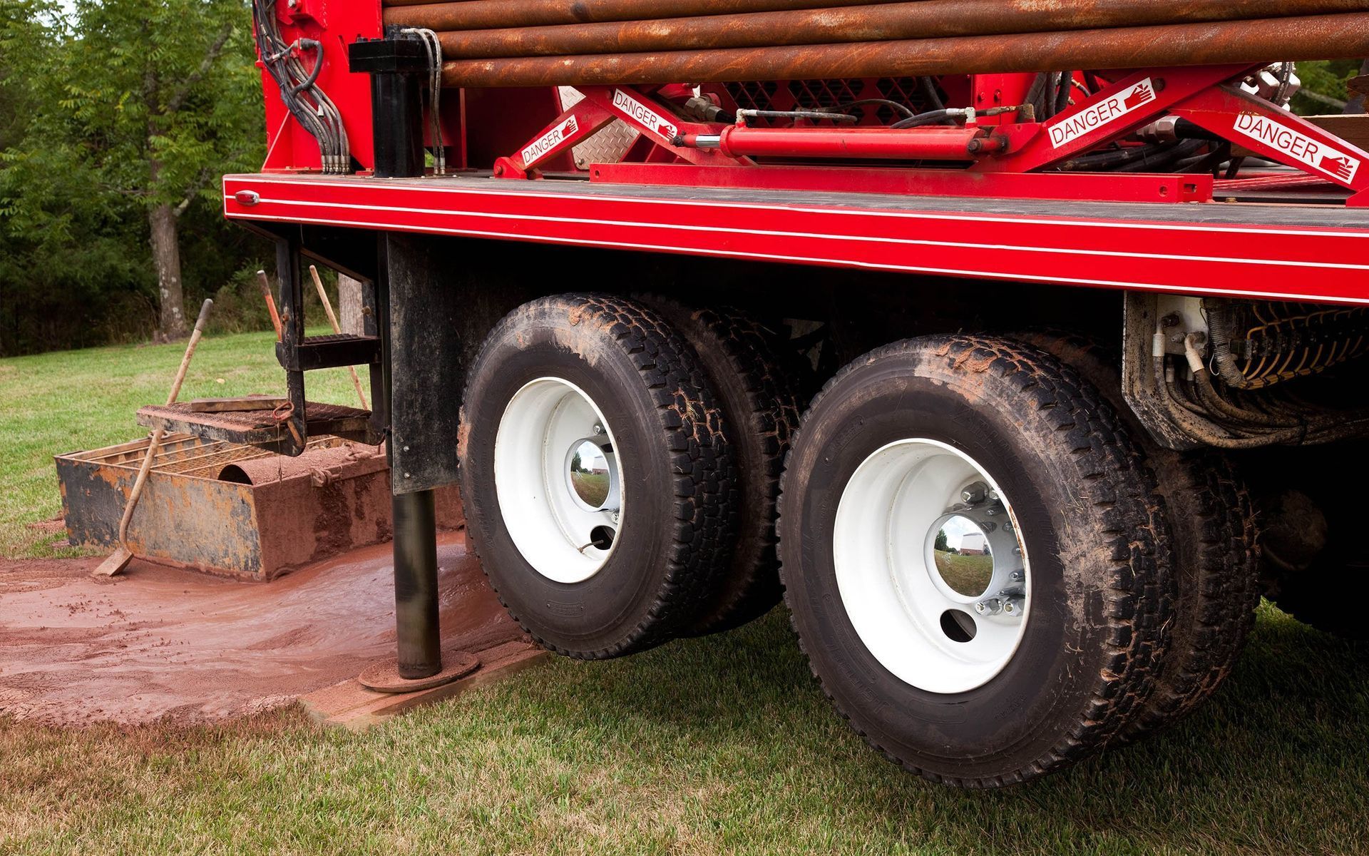 A red truck with white tires is parked in a grassy field.