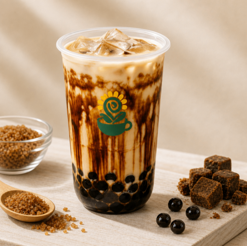 Iced bubble tea with black tapioca pearls and brown sugar drizzle in a clear cup with a green logo.