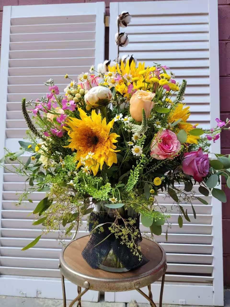 Colorful mixed flower bouquet with sunflowers and pink roses in a vase on a round table