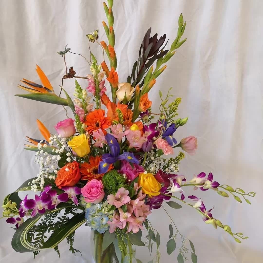Colorful mixed flower bouquet with orange, purple, pink, and yellow blooms against a white background