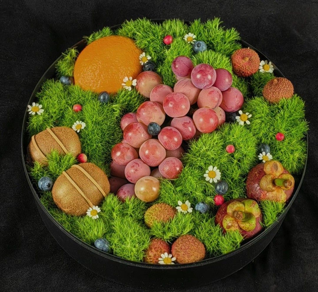 Assorted fruit arranged in a decorative round tray with green garnish and small flowers