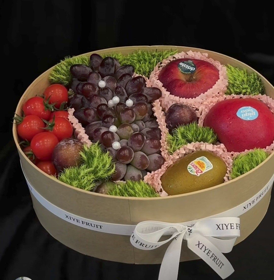 Gourmet fruit gift box with grapes, strawberries, apples, kiwi, and other fresh fruit in a round hatbox