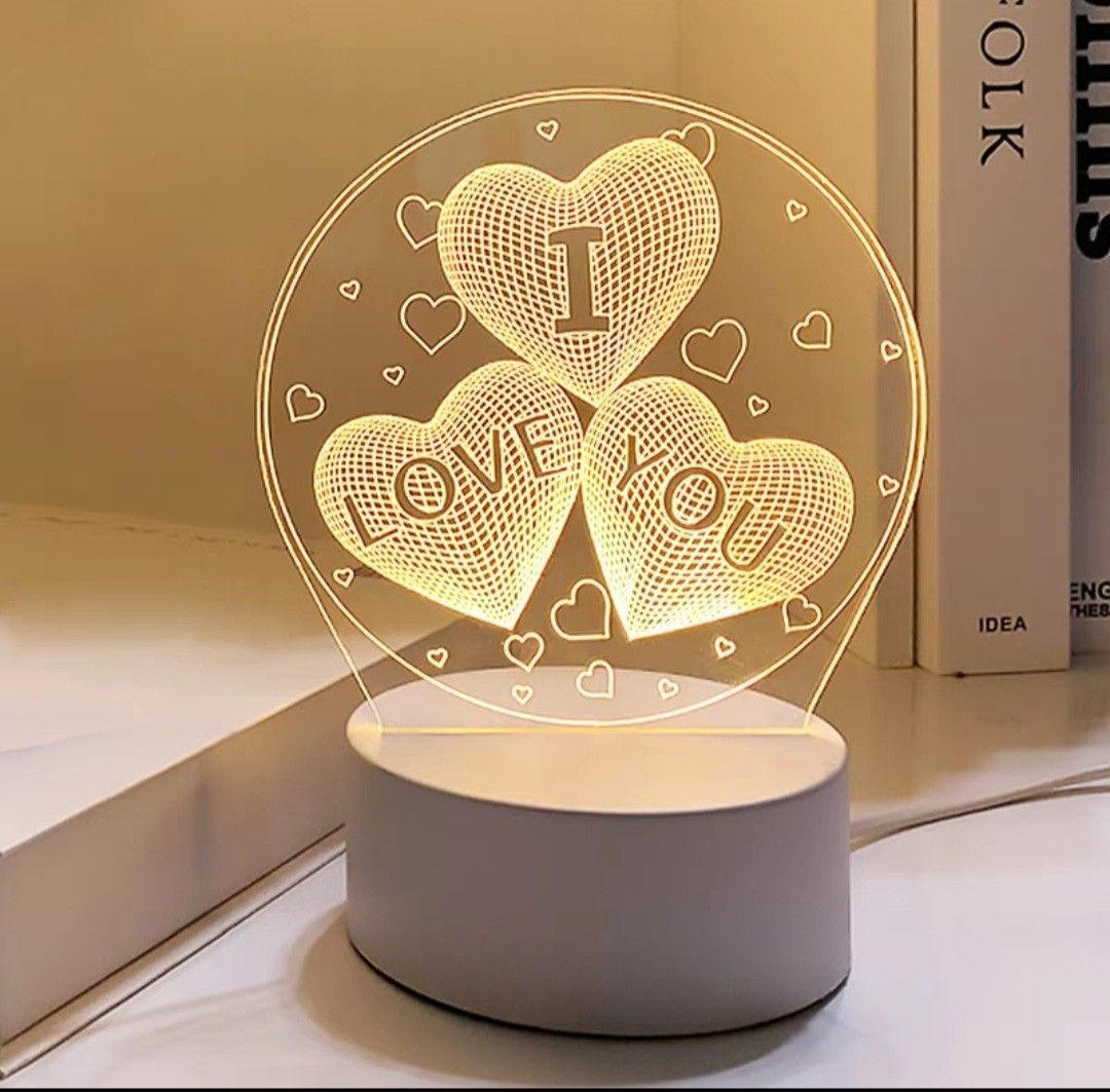 Heart-shaped “I LOVE YOU” LED lamp glowing on a white base on a tabletop.