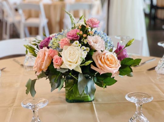 Pink and white floral centerpiece in a glass vase on a banquet table