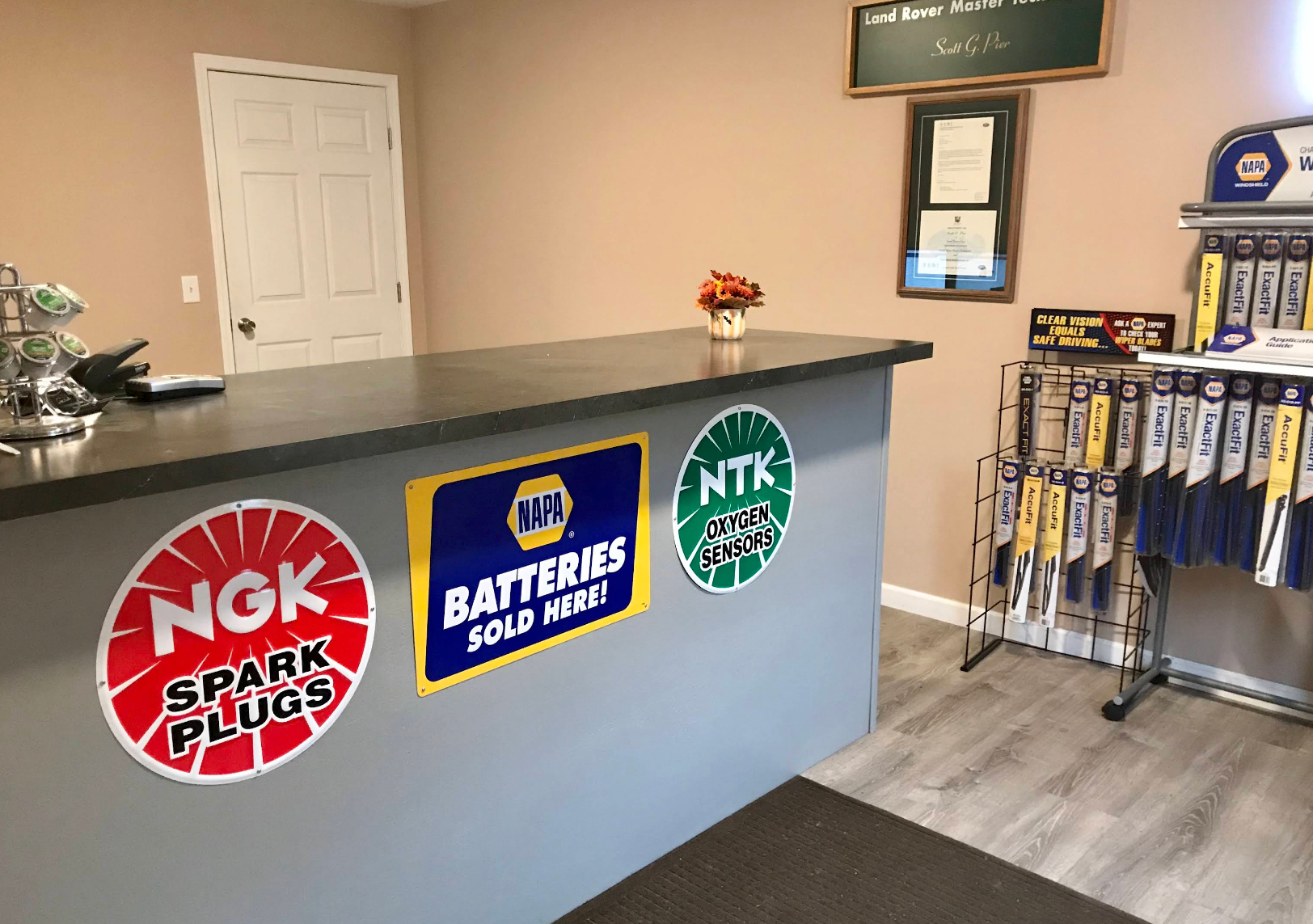 Auto parts counter with NGK, Mazda, and NTK logos, brochures, and a display rack in a small showroom | Discovery Automotive