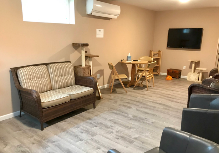 Living room with wicker sofa, chairs, TV, and light wood flooring | Discovery Automotive