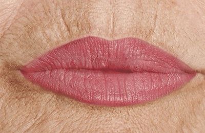 Eine Nahaufnahme der Lippen einer älteren Frau mit rosa Lippenstift.