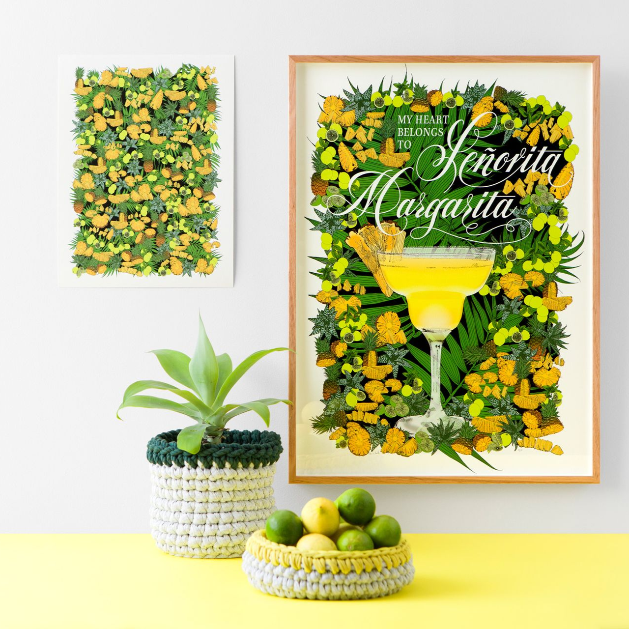 Framed green-and-yellow cocktail art with citrus decor and a potted plant on a white shelf