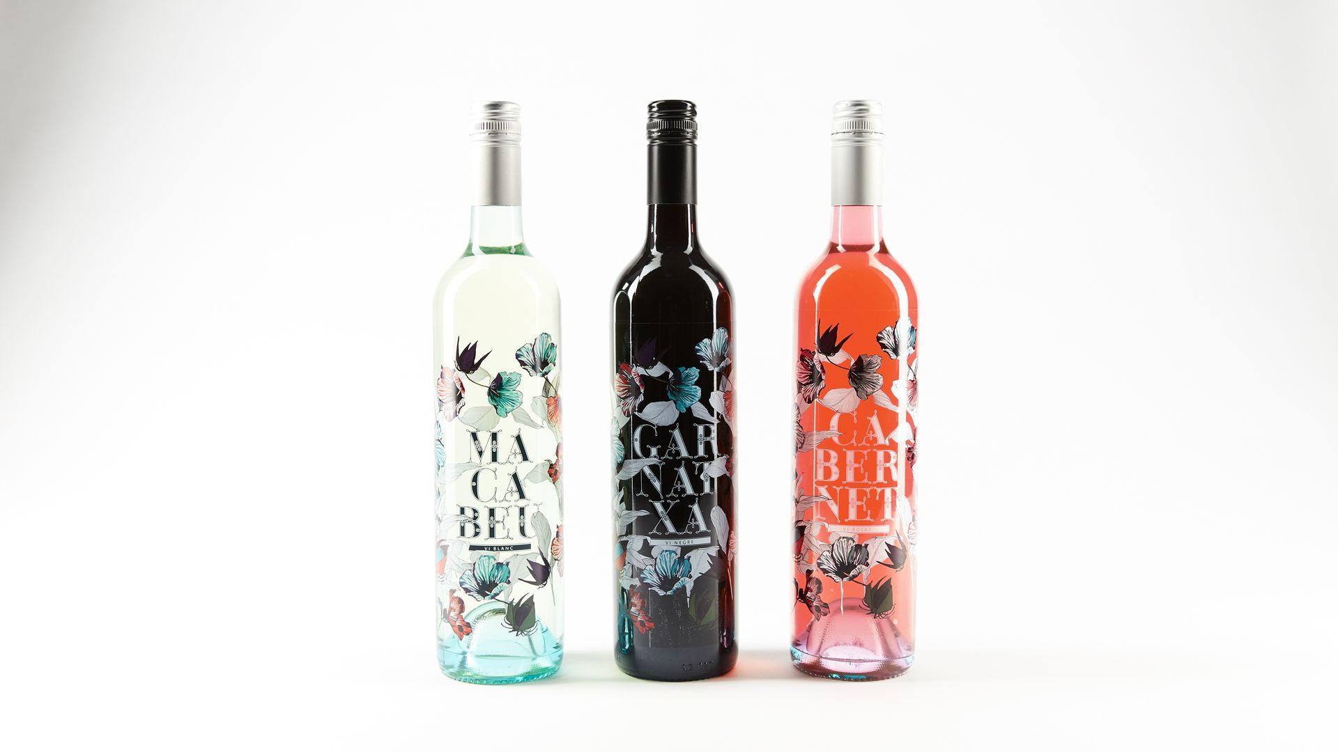Three decorative wine bottles standing side by side on a white background.