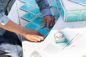 pool contractor laying blue tiles on the pool steps