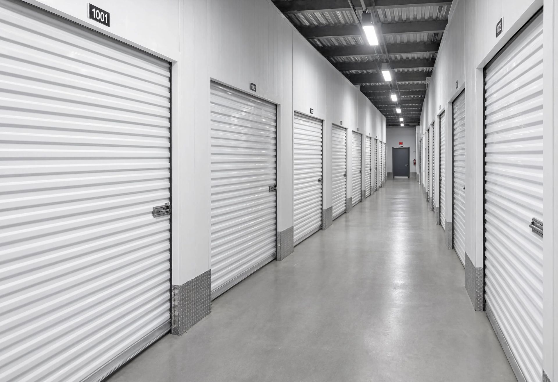 Modern self storage facility corridor featuring secure metal roll up doors, clean organized rental units