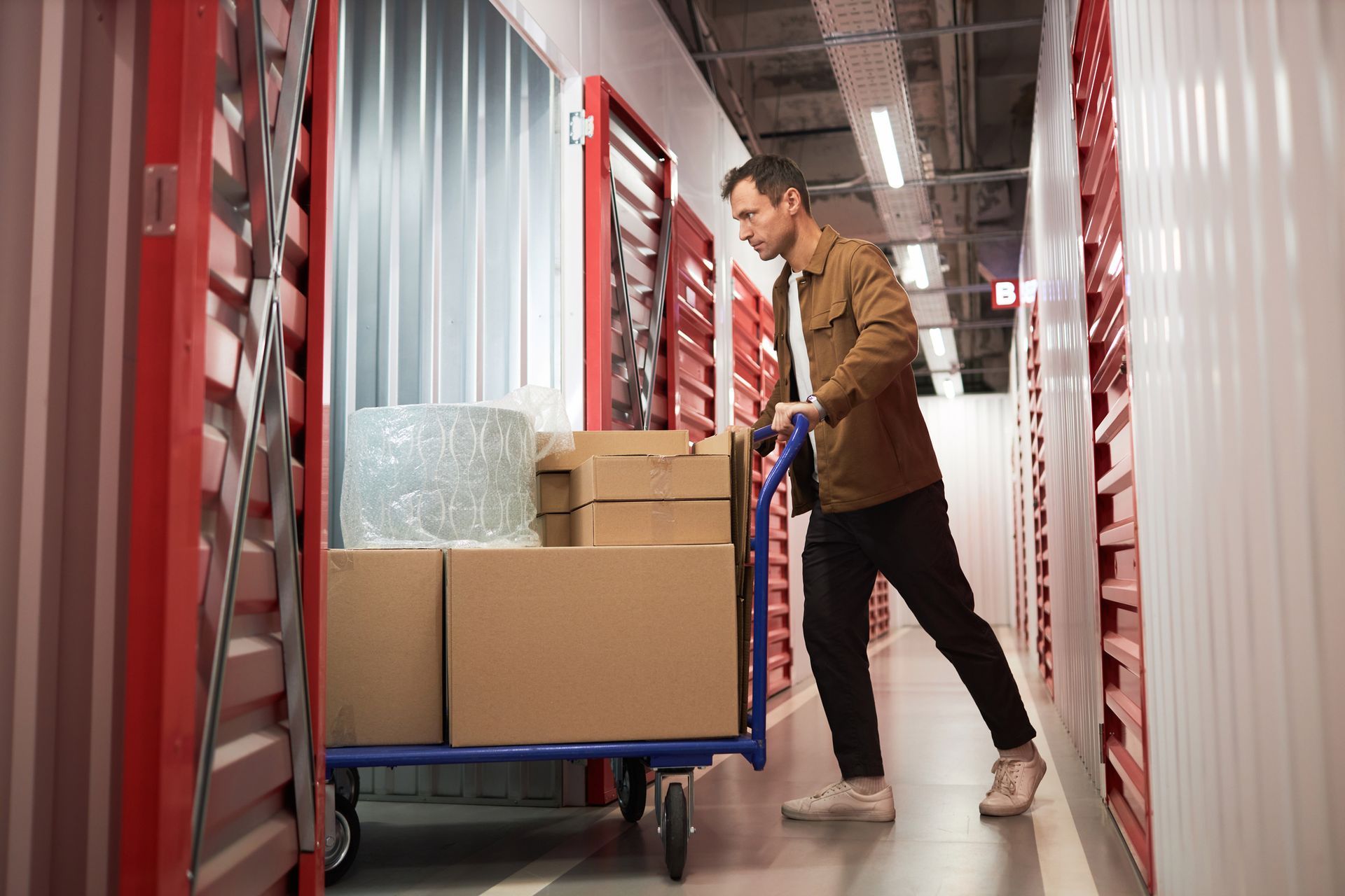 A man pushing a cart with boxes inside a storage unit. A man pushing a cart with boxes inside a storage unit.