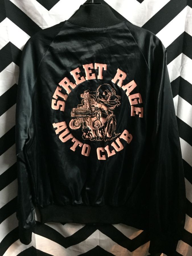 Black jacket with “Street Ride Auto Club” graphic on the back hanging against a black-and-white chevron background