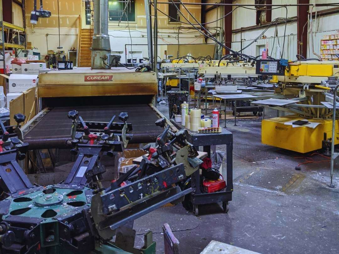 Factory floor with machinery and equipment, including a large yellow industrial machine and metal frames.