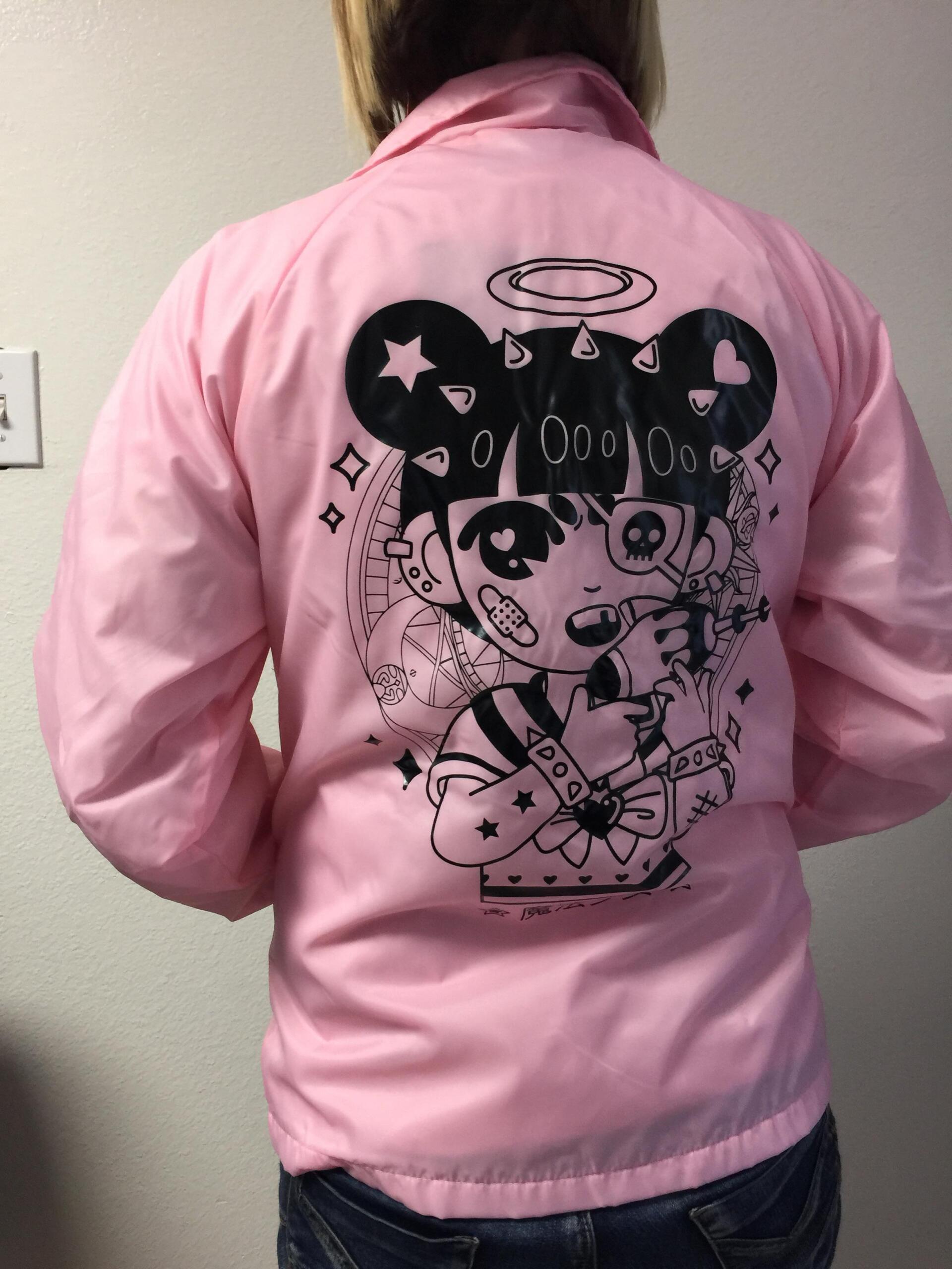 Person wearing a pink jacket with a cartoon graphic on the back, viewed from behind.