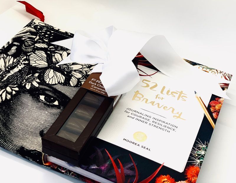 Gift box with black-and-white patterned wrapping, a white tag, and a small dark bottle tied with a ribbon.