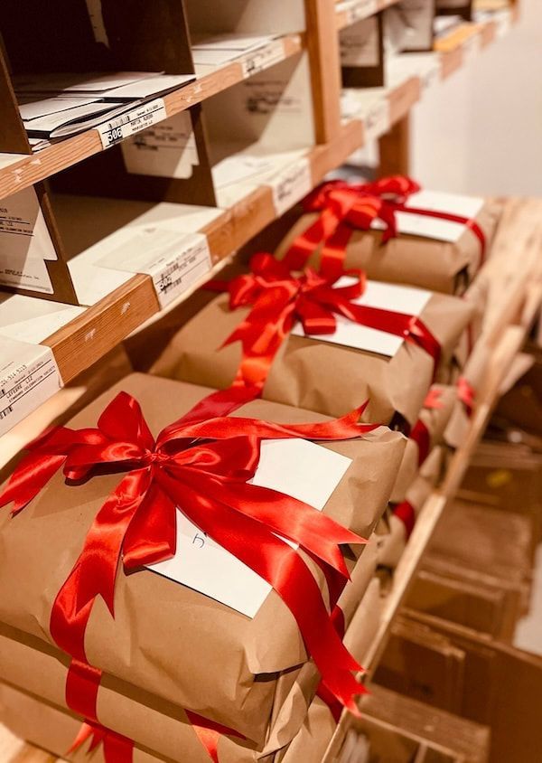 Wrapped gifts with red ribbons stacked on store shelves