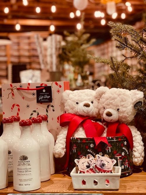 Holiday gift display with teddy bears, red ribbons, candles, and festive decorations on a table