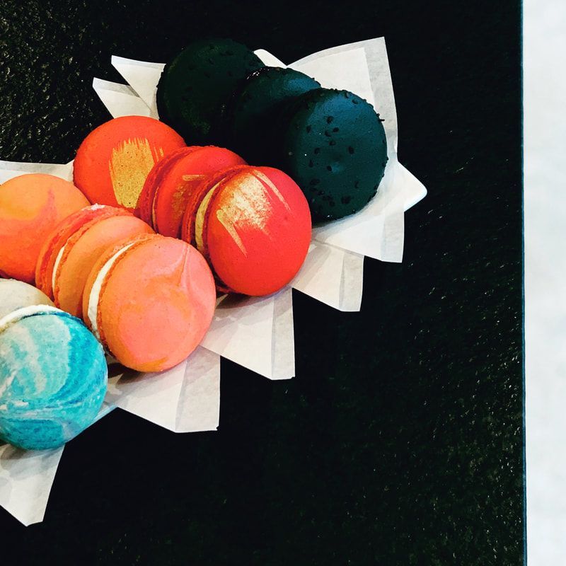 Colorful macarons in white paper holders on a dark background