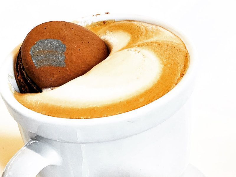 White coffee cup with latte art and a chocolate truffle topped with cocoa powder