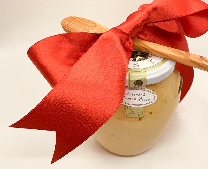 Glass jar with a red ribbon bow and wooden spoon, filled with pale cream on a white background