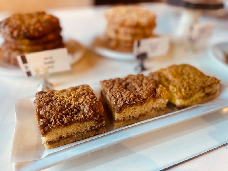 Tray of square crumb-topped dessert bars on a white platter at a buffet table