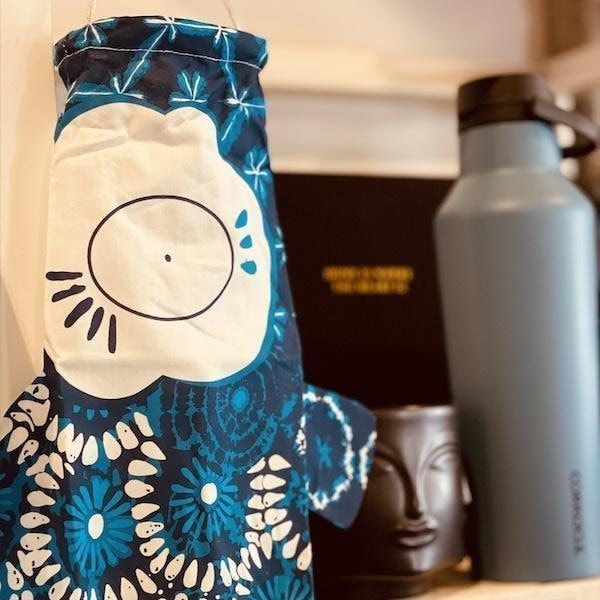 Blue patterned fabric-wrapped bottle beside a gray bottle and black mug on a countertop
